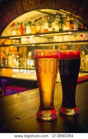 2 beer glasses on the bar counter in the half-dark