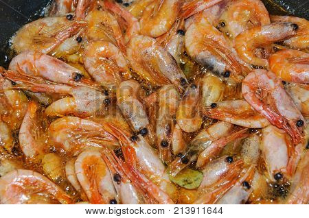 appetizer shrimp stir-fried in boiling olive oil in a cast iron skillet