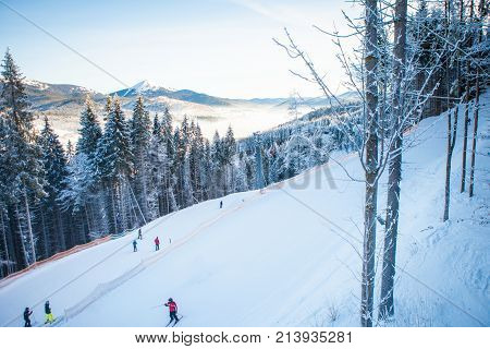 Skiers on the ski lift riding up at ski resort with beautiful background of snow-covered slopes, forests, hills in Bukovel, Ukraine