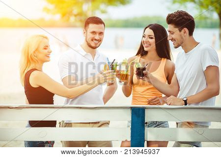 Friends having fun at the bar outdoors, drinking cocktails. Summer bar Sun flare