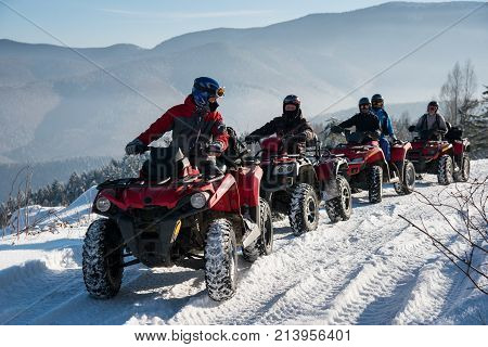 Group Of People Driving Off-road Quad Bikes On Snow At Top Of The Mountain In Winter