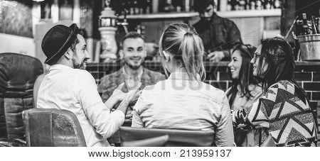 Trendy friends chatting and laughing together inside cocktail fashion bar - Cheerful people having fun doing pre dinner appetizer - Soft focus on left man face - Black and white editing
