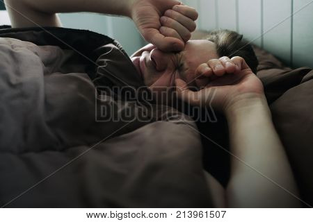 offended caucasian man lie on bed and cover himself with blanket. He is about to cry. Negative human emotion.