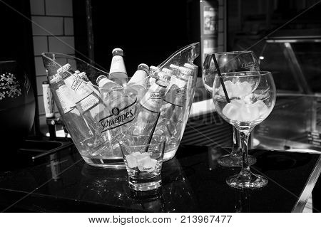 Key west Fl USA - March 30 2016: Schweppes Tonic Water bottles yellow color in glass with cold ice cubes on table near bocals of lemon beverage with drinking straw