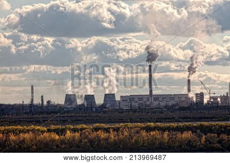 a huge factory. many pipes smoke black smoke in the blue sky. violation of environmental cleanliness. horizontal frame. ecological catastrophy. Apocalypse