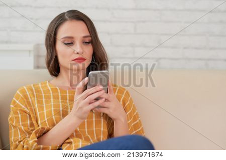 Pretty young woman reading text message on her smartphne