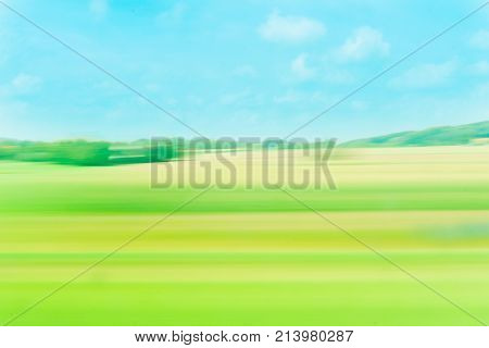Abstract background color surge green and brow and blue tones of fields and countryside from moving train window