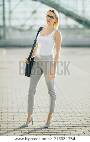 The image of a business woman standing on the street at sunset