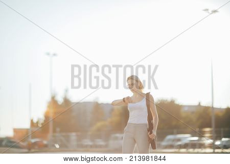 Attractive business woman using a phone and clock while standing in front of windows in an office building overlooking the city