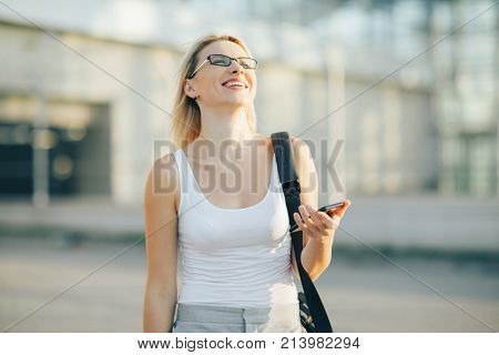 Blonde Business woman reads a message on the phone and smile