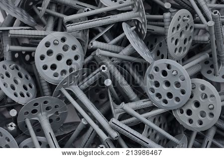 Background Pattern Of Many Gray Plastic Dowels (fastening) For Thermal Insulation. A Huge Pile Of Fi