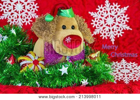 new year toy dog surrounded by decorative Christmas elements and fir branches on red background. Merry Christmas