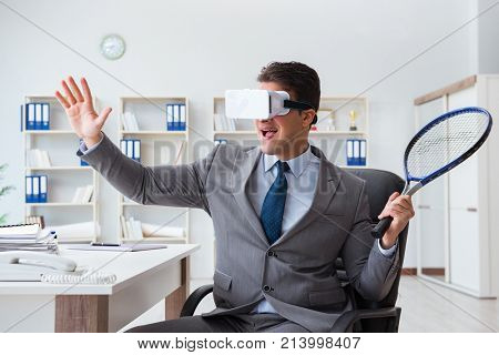 Businessman playing virtual reality tennis in office with VR gog