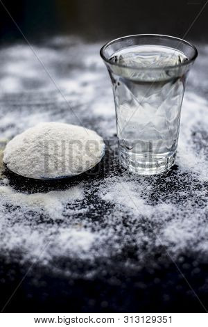 Rice Water In A Glass Bowl Along With Rice Grains & Its Powder Also On Wooden Surface & Some Rice Po