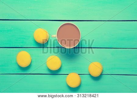 A Cup Of Coffee And Yellow Macaroons On A Blue Wooden Table. Trend Of Minimalism. Top View.