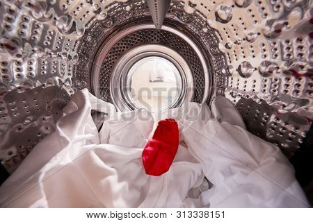 View Looking Out From Inside Washing Machine With Red Sock Mixed With White Laundry