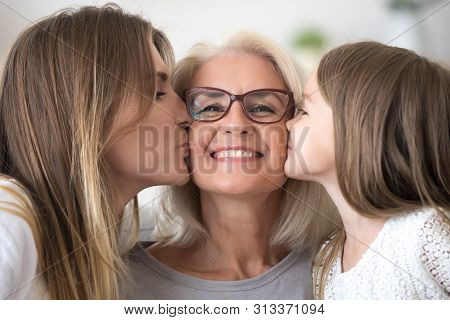 Portrait Of Granddaughter And Daughter Kissing Grandmother