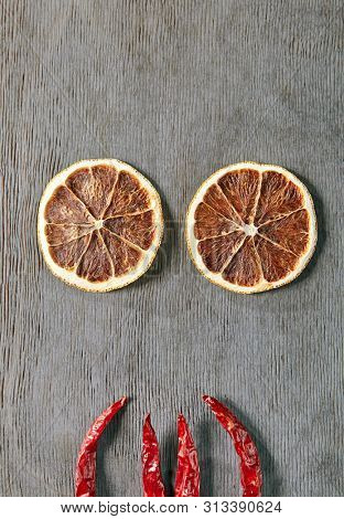 Food Art Concept with Abstract Halloween Monster made of Dried Orange Slices and Chili Pepper Top Vew. Creative Layout with Eyed Human Face made of Flat Lay Products