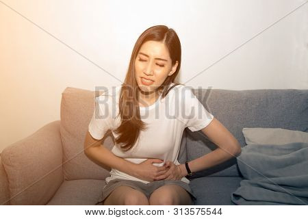 Pretty Asian Woman Holds Her Stomach With Both Hands. Stomach Upset Or Pain During Menstruation.