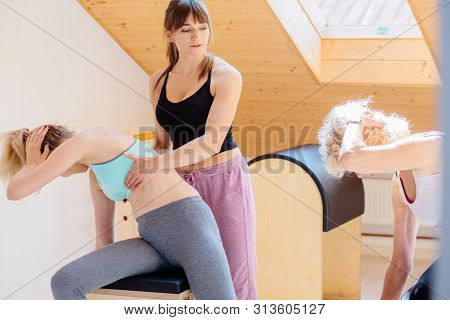 Two Different Age Women Clients Exercising On Pilates Combo Wunda Pilates Chair With Woman Instructo