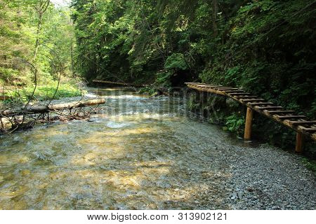 A Wooden Footbridge Running Along A Larger Stream In The Slovak Paradise National Park