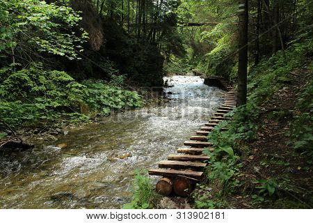 A Wooden Footbridge Running Along A Larger Stream In The Slovak Paradise National Park
