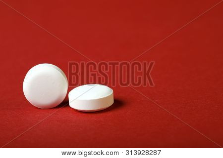 A Group Of White Pills On A Red Background. Cropped Shot, Horizontal, Side View, Close-up. The Conce