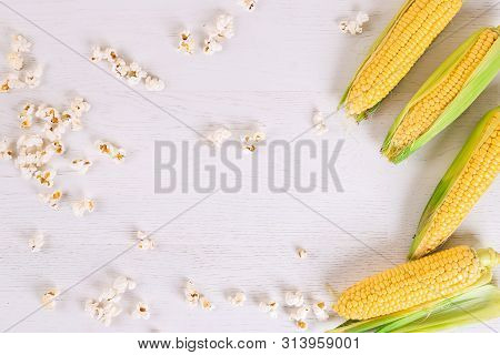 Fresh Corn Cobs And Popcorn On Wooden White Background. Copy Space. Flat Lay
