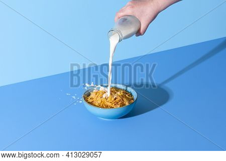 Pouring Milk From A Bottle Into A Bowl With Cornflakes Cereals. Bowl With Corn Cereals And Milk Isol