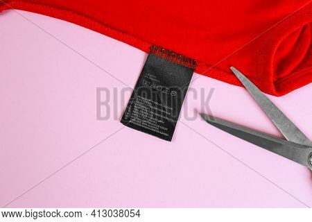A Pair Of Scissors Cutting A Tag Off. Tag Trim On Baby Clothes, Close Up.tags That Pierce The Skin
