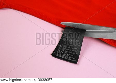 A Pair Of Scissors Cutting A Tag Off. Tag Trim On Baby Clothes, Close Up.tags That Pierce The Skin