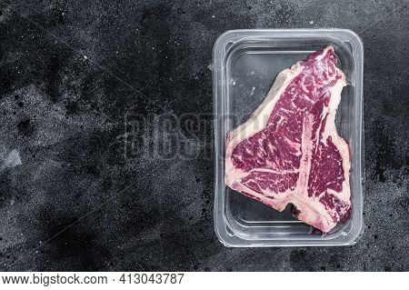 T-bon Raw Beef Steak In Vacuum Packaging. Black Background. Top View. Copy Space