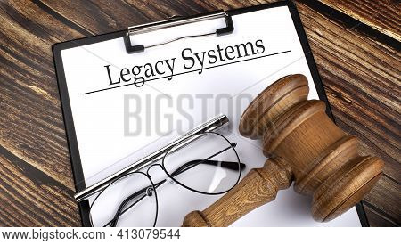 Paper With Legacy Systems With Gavel, Pen And Glasses On Wooden Background