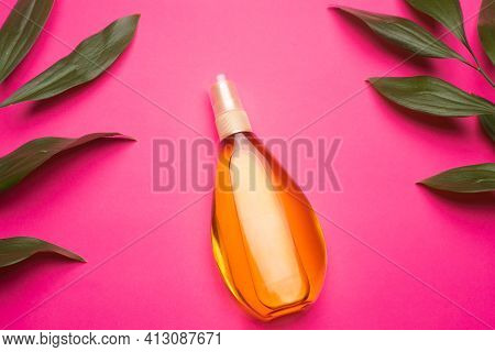 Suntan Oil On A Pink Background . Suntan Oil And Green Leaves. Vacation. Protect Your Skin From The 