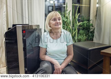 Senior Woman Sitting Near Portable Air Purifier In The Living Room At Home, New Technology To Protec