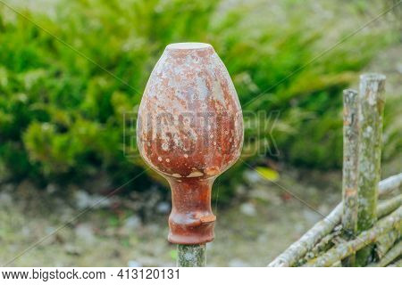 Antique Clay Jug Hanging On A Wicker Fence