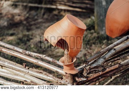 The Remains Of An Old Clay Pot Hang On A Wicker Fence