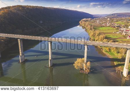Aerial View Of The Road Bridge Over Dniester River, Hills, And Ustechko Village On The Bank On An Au
