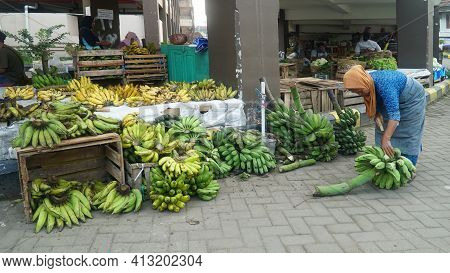 Magelang, Indonesia. March 11, 2021: An Old Woman Selling Fruit Is Cutting Bananas At Muntilan Marke