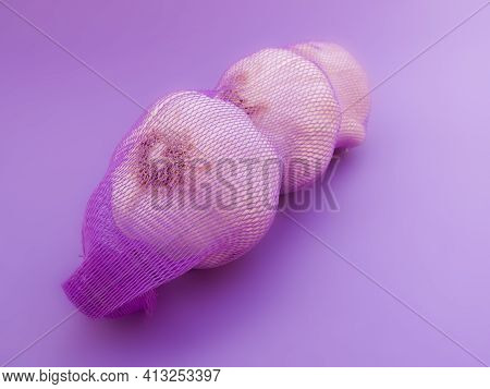 Garlic In Net. Garlic Packaging Nets. Three Garlic Heads Packaged In A Mesh Bag. Fresh Garlic Head W