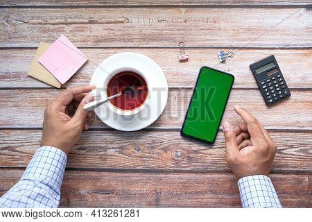 Top View Of Man Hand Using Smart Phone On Office Desk