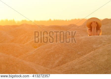 Young Beautiful Lonely Woman With Long Hair With Straw Hat On Headlying On Sand, Closing Face With H