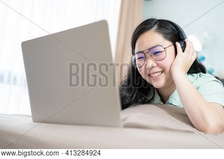 Beautiful Asian Woman Is Using A Headset With Laptop And Lying On The Bed In Her Bedroom With A Past