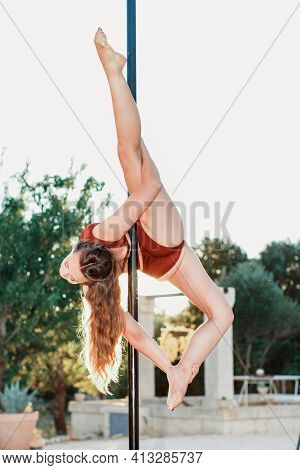 Young Pole Dancer Posing On A Portable Platform Against The Garden. Athletic Caucasian Woman Trainin