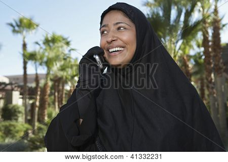 Gelukkig Indiase vrouw in burka communiceren op mobiele telefoon