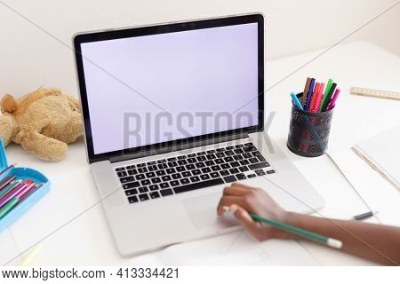 Hand of african american girl in bedroom using laptop with copy space for online school lesson. staying at home in isolation during quarantine lockdown.