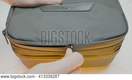 Moscow, Russia - December, 2020: Close-up Of Man Opening Bag From Camera. Action. Hands Open Zip Of 