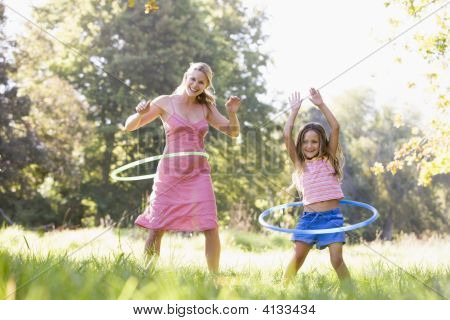 Nő és fiatal lány a szabadban mosolyogva Hula Hoops