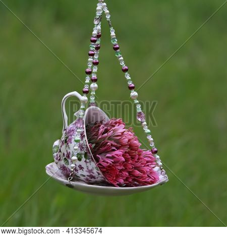 Pink Wildflowers In A Purple Chintz Floral Vase Hanging Outside
