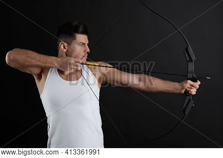 Man With Bow And Arrow Practicing Archery On Black Background